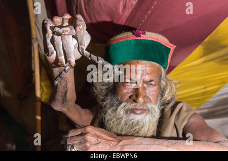 Juna Akhara Shiva de sadhu, saint homme, la pratique de Urdha Tapa, levant un bras depuis de nombreuses années pour des raisons spirituelles, dans sa tente. Banque D'Images