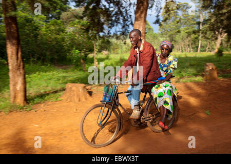 Man riding a bike avec une femme en vêtements traditionnels africains sur le transporteur, Burundi, Cankuzo, près de Parc National de la Ruvubu, Cankuzo Banque D'Images