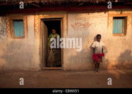 Femme avec balai debout dans l'entrée, garçon appuyé contre la façade, Burundi, Karuzi, Buhiga Banque D'Images