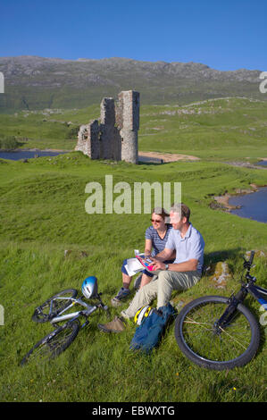 Couple après bikeride aux côtés d'Ardvreck Castle, Loch Assynt, Royaume-Uni, Ecosse, Sutherland Banque D'Images