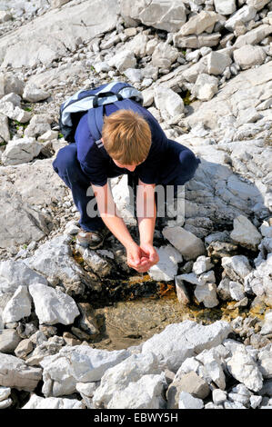 Jeune garçon l'eau potable à partir d'un ruisseau de montagne, Allemagne, Bavière, Allgaeu Banque D'Images