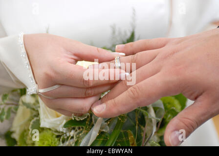 Mariée de mettre l'anneau de mariage de l'époux. Banque D'Images