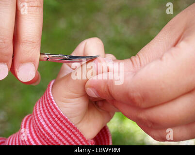 Mains d'un adulte un peu coupe ongles de l'enfant Banque D'Images