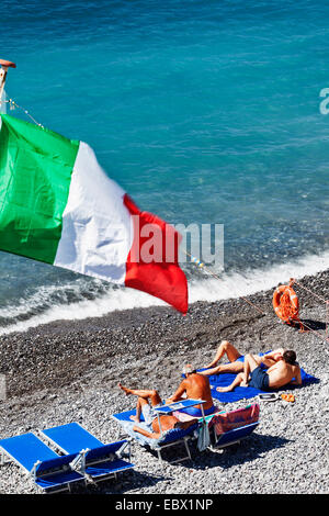 Les touristes sous le drapeau italien sur la plage de galets. Banque D'Images