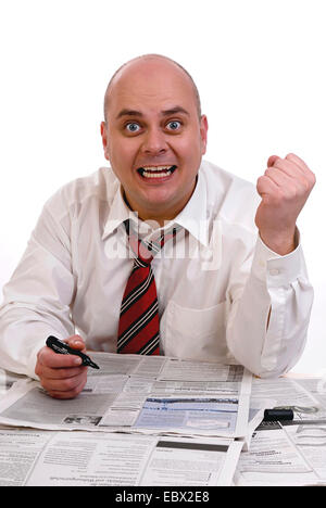 L'homme avec le marqueur à la main à partir d'un papier avec les annonces d'emploi de rire et avec les poings serrés Banque D'Images