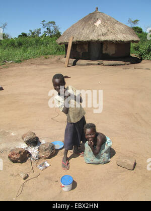 Camp de réfugiés pour les personnes déplacées dans le nord de l'Ouganda autour de Gulu, simple maison de terre en arrière-plan, les enfants jouant à Gulu, en Ouganda, cheminée Banque D'Images