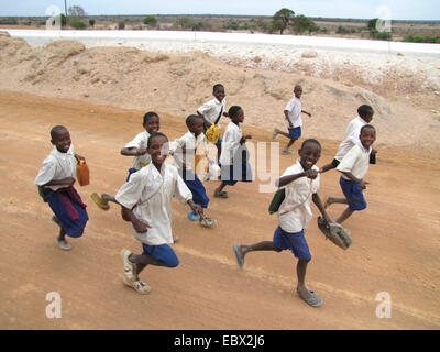 Les enfants en uniforme scolaire s'exécutant sur route non revêtue avec un sourire près de la capitale administrative, de la Tanzanie, Dodoma, Dodoma Banque D'Images