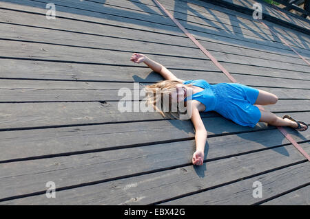 Jeune femme blonde allongée sur un plancher en bois Banque D'Images