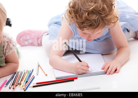 Les petites filles se trouvant sur le dessin avec crayons grond Banque D'Images