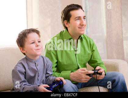 Père et fils avec des manettes de jeux vidéo Banque D'Images