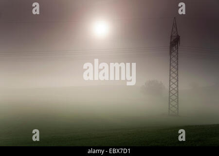 Soleil levant franchir matin brouillard sur une prairie paysage avec une ligne à haute tension, l'Allemagne, la Saxe, Vogtlaendische Schweiz Banque D'Images