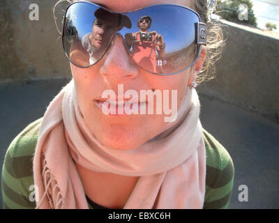 Femme portant des lunettes de soleil, le photographe se reflète dans les lunettes de soleil Banque D'Images