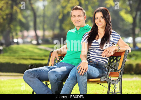 Jeune couple assis sur un banc de parc sur une belle journée d'été Banque D'Images