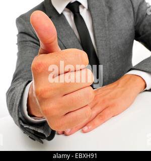 Homme portant un costume assis dans une table donnant un signal de Thumbs up Banque D'Images