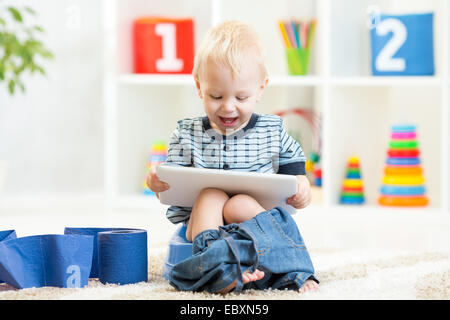 Smiling enfant assis sur le pot de chambre avec du papier toilette Banque D'Images