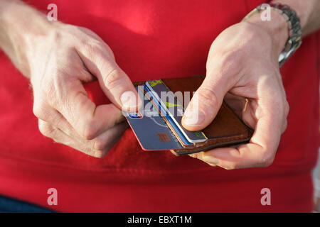 Un homme en rouge haut retrait d'une carte de crédit de la banque nationale à partir d'un porte-monnaie pour payer un achat. En Angleterre, Royaume-Uni, Angleterre Banque D'Images