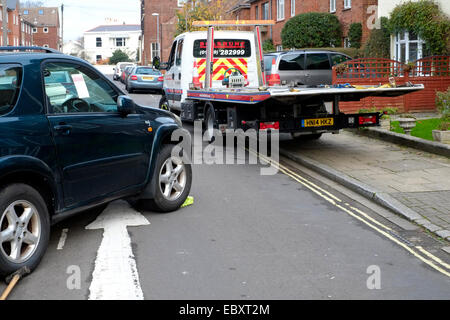 Une voiture d'être saisi et remorqué dans un milieu urbain uk street Banque D'Images