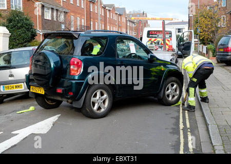 Une voiture d'être saisi et remorqué dans un milieu urbain uk street Banque D'Images