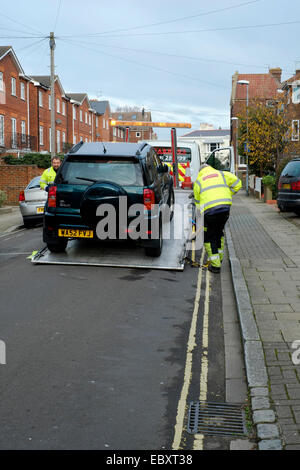 Une voiture d'être saisi et remorqué dans un milieu urbain uk street Banque D'Images