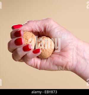 Noix dans a woman's hand soient écrasés Banque D'Images