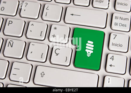 Clavier espagnol avec de l'énergie eco light ampoule enregistrer icône sur fond vert bouton. Image avec chemin de détourage pour le changement facile Banque D'Images