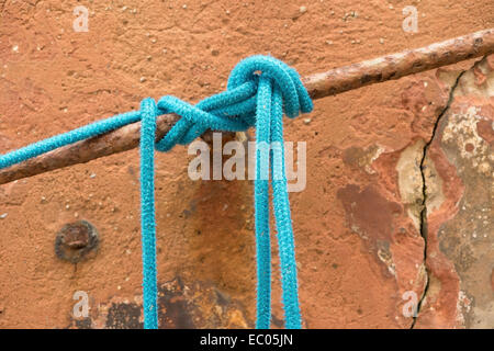 Un nylon bleu corde d'amarrage d'un bateau, attaché à une barre d'un port de pêche. Banque D'Images