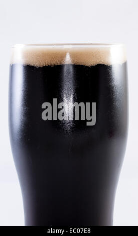 Pinte de stout en verre sur un fond blanc. Banque D'Images