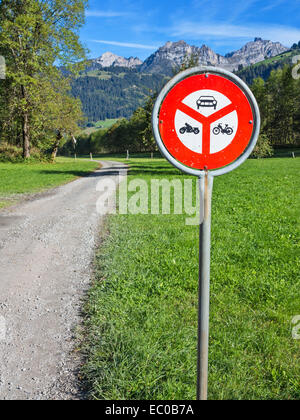 Un roadsign sur une route de gravier qui longe une vallée alpine, interdisant l'entrée pour les véhicules motorisés Banque D'Images