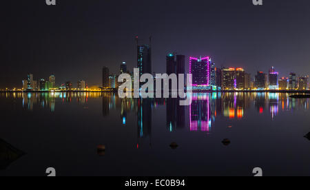 Nuit ville moderne skyline panorama avec néons lumineux et reflet dans l'eau. Manama, la capitale de Bahreïn, au Banque D'Images