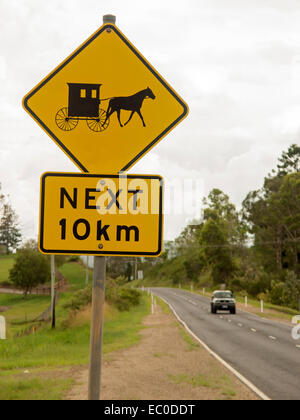 Jaune officiel & black road sign pilotes d'alerte à surveiller les véhicules tirés par des chevaux pour le prochain 10km - avec voiture moderne sur route Banque D'Images