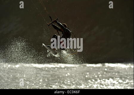 Kite surfer en spray silhouetté comme il vole haut au-dessus de la vague Banque D'Images