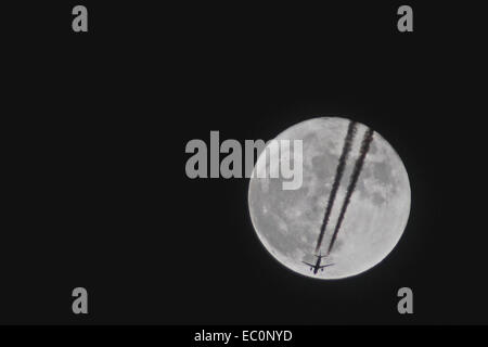 UK. 6e déc, 2014. Météo : Un avion de ligne et c'est des traînées de vapeur sont découpé sur une pleine lune sur la Manche. Credit : Graham mitchell/Alamy Live News Banque D'Images