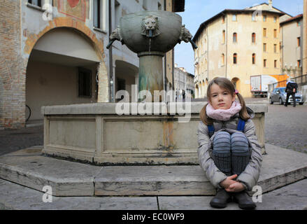 Une petite fille à la fontaine qui persiste sur la Piazza San Marco, une place dans le centre historique de la ville de Pordenone, Italie. Banque D'Images