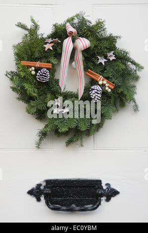 Une couronne de Noël est suspendu à la porte avant en bois peint blanc d'une traditionnelle maison de campagne dans le Peak District, UK Banque D'Images