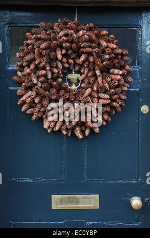 Un cadre rustique, cone-paniers-couronne de Noël est suspendu à la porte avant d'une traditionnelle maison de campagne dans le Peak District, UK Banque D'Images