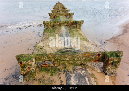 Début 20C d'acier ou en sortie de l'eau pluviales découverte à marée basse protégé par un revêtement en béton des dommages et des barres de traverse Banque D'Images