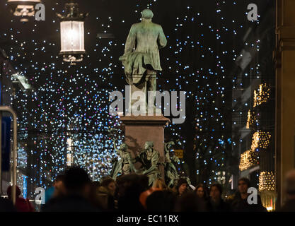 Les personnes à la gare centrale de Zurich se déplacer après la statue d'Alfred Escher avec l'éclairage de la ville de Noël lumineux à l'arrière. Banque D'Images