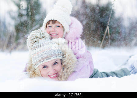 Heureux parent et enfant jouant avec la neige en hiver piscine Banque D'Images