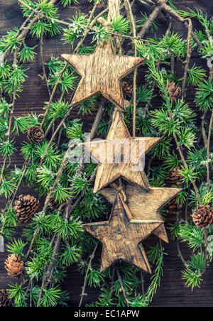 Décorations de Noël étoiles en bois de pin et des branches d'arbre. jours fériés. fond ocre de style vintage photo Banque D'Images