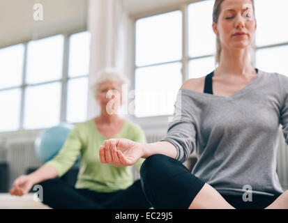 Tourné à l'intérieur de la médiation des femmes dans la classe de yoga. Se concentrer sur la main. Les femmes pratiquant le yoga fitness détendue au sport. Banque D'Images