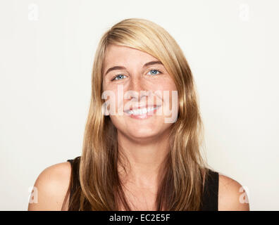 Jeune femme qui a l'air dans l'appareil photo avec de longs cheveux raides, portrait Banque D'Images