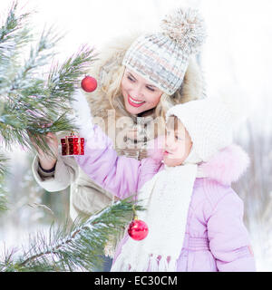 Happy mother and child decorating Christmas Tree outdoor hiver Banque D'Images