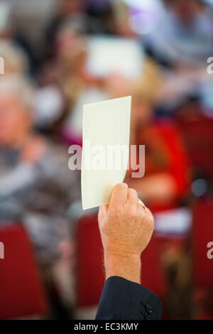 Locataires holding up leurs cartes de vote des actionnaires à l'assemblée générale annuelle de l'association du logement de Tai Ceredigion, pays de Galles, Royaume-Uni Banque D'Images