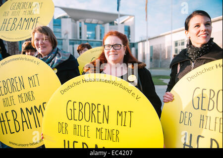 Berlin, Allemagne. 09Th Dec, 2014. Les membres de l'Association des sages-femmes allemandes (DHV) rassemblement devant la chancellerie à Berlin, Allemagne, 09 décembre 2014. Ils portent des signes qui lisez 'né avec l'aide de mon sage-femme". Photo : Felix Zahn/dpa/Alamy Live News Banque D'Images