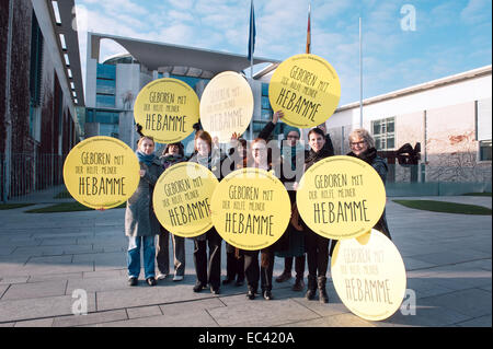 Berlin, Allemagne. 09Th Dec, 2014. Les membres de l'Association des sages-femmes allemandes (DHV) rassemblement devant la chancellerie à Berlin, Allemagne, 09 décembre 2014. Ils portent des signes qui lisez 'né avec l'aide de mon sage-femme". Photo : Felix Zahn/dpa/Alamy Live News Banque D'Images