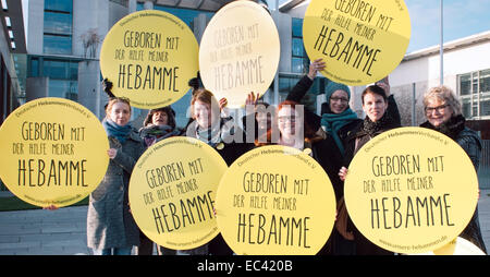 Berlin, Allemagne. 09Th Dec, 2014. Les membres de l'Association des sages-femmes allemandes (DHV) rassemblement devant la chancellerie à Berlin, Allemagne, 09 décembre 2014. Ils portent des signes qui lisez 'né avec l'aide de mon sage-femme". Photo : Felix Zahn/dpa/Alamy Live News Banque D'Images