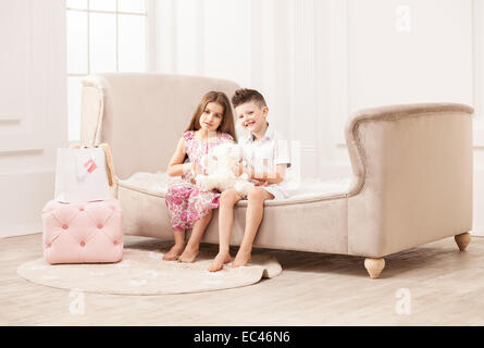 Jeune garçon et fille jouant avec ours assis sur la table Banque D'Images