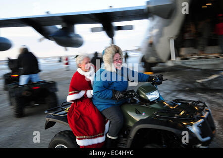 Mme Santa Claus de sur un ATV pendant la visite d'un village Inuit à distance dans le cadre de l'Opération Père Noël 16 décembre 2009 à Gambell, Alaska. L'opération Père Noël a remis un don de cadeaux aux pauvres des villages de l'Alaska à distance par le transport de l'Armée de l'air depuis 1951. Banque D'Images