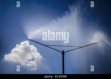 D'un système sprinkleur pulvérise un rideau d'eau contre le ciel bleu Banque D'Images