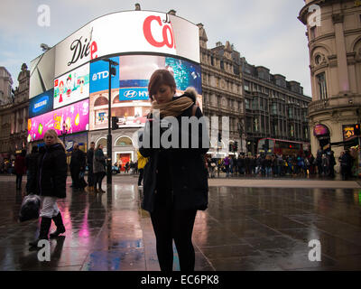 Une jeune femme s'arrête pour vérifier son téléphone portable à Piccadilly Circus, Londres, Angleterre Banque D'Images